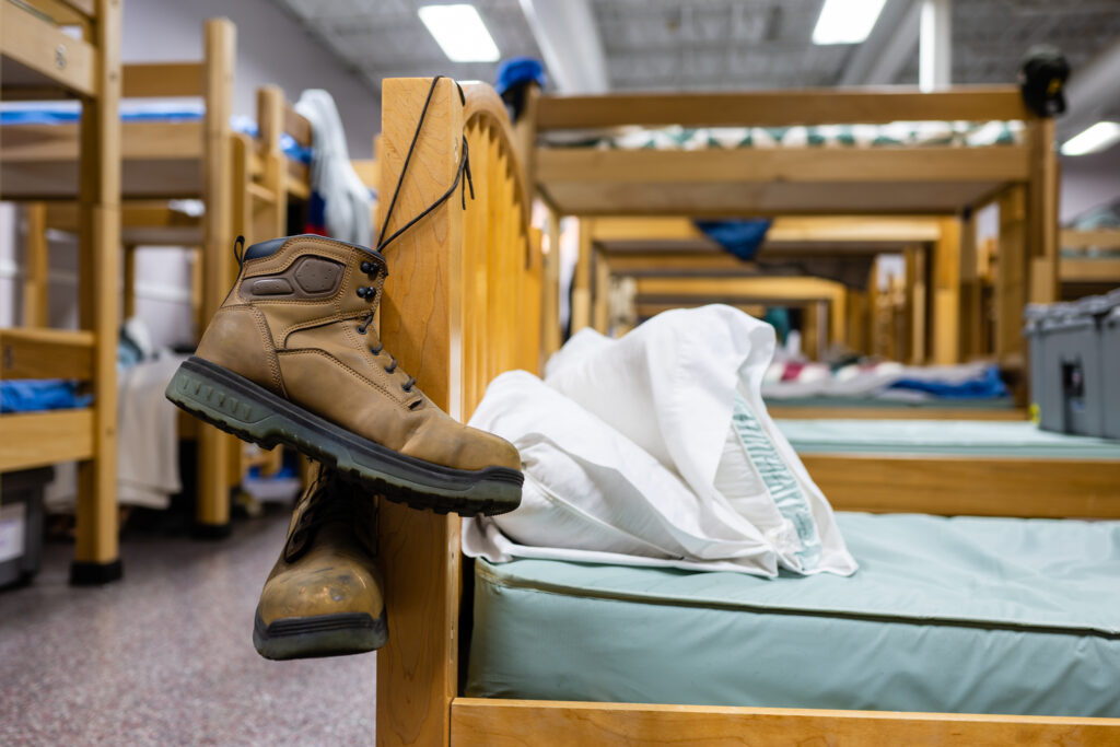 A pair of work boots hanging from a bedpost in the C-U Men's Shelter