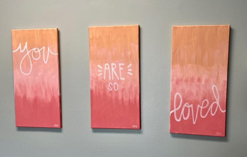 A triptych of paintings which reads, "You are so loved"